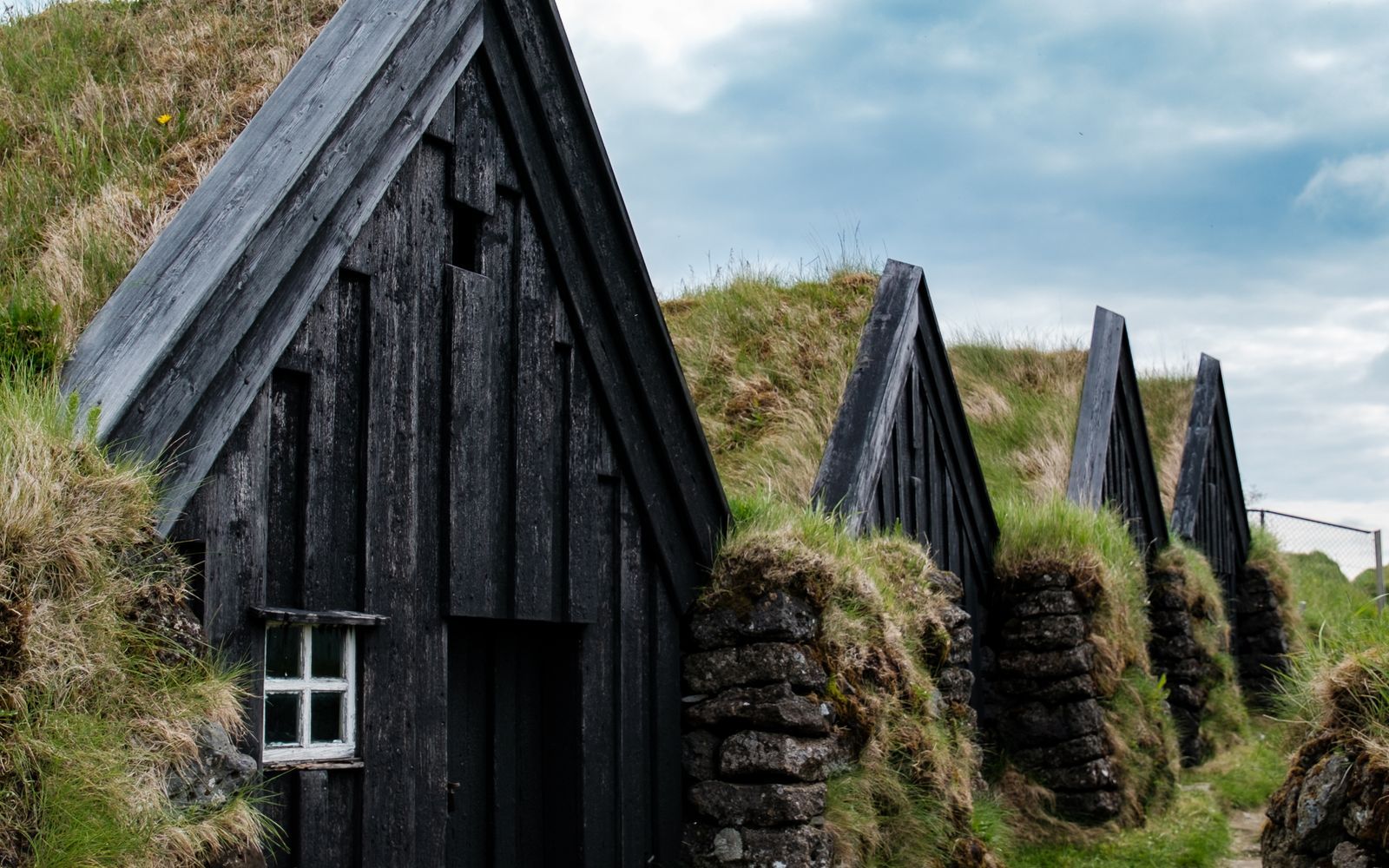 Turf-roofed Icelandic buildings beneath a mountain